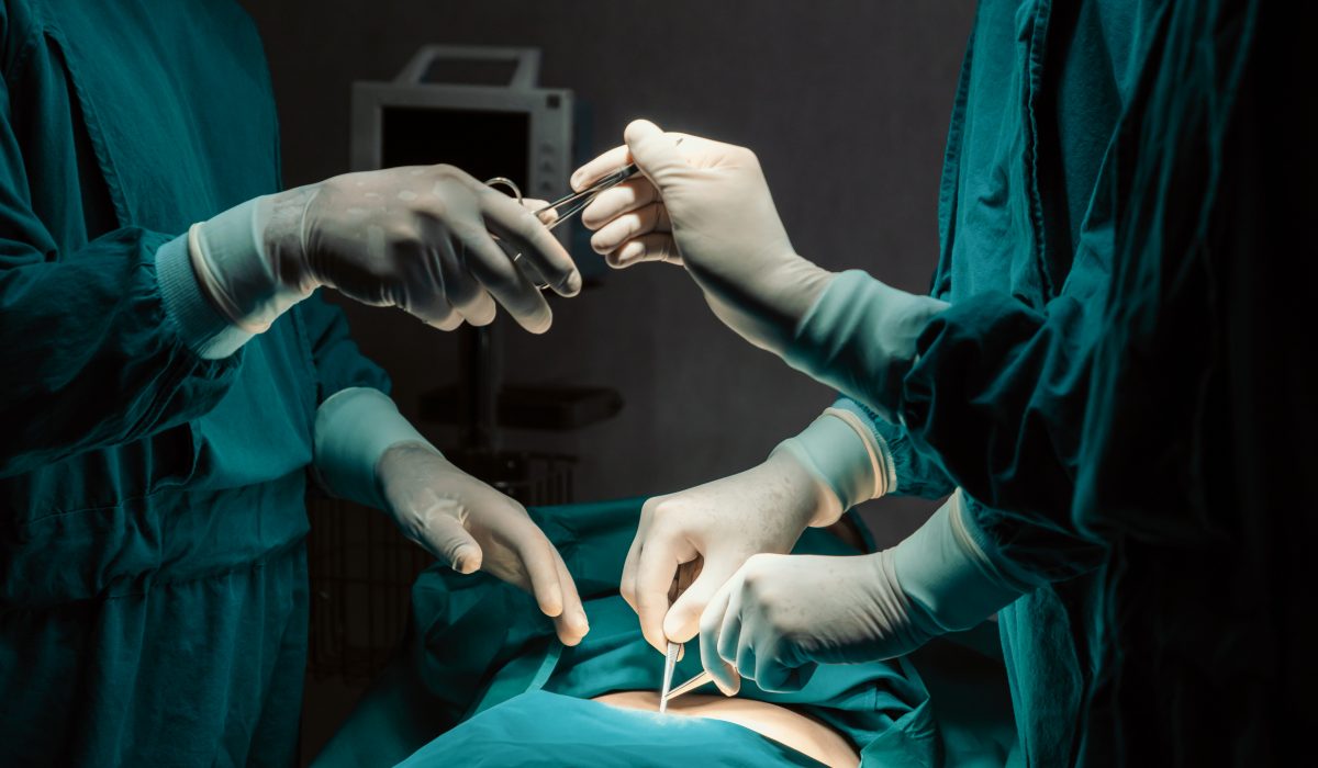 Image of surgical team perform surgery operation, nurse hand out sterile scissors to surgeon as supportive and cooperative in operation room concept.